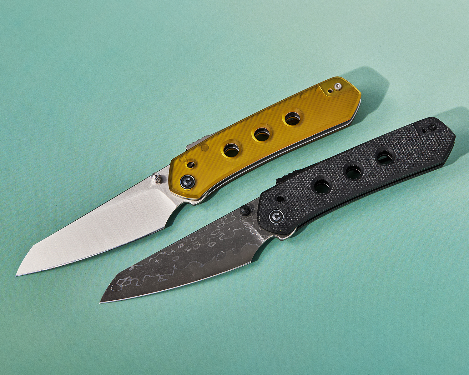 Two CIVIVI Vision FG folding knives, open, displayed side-by-side on green background