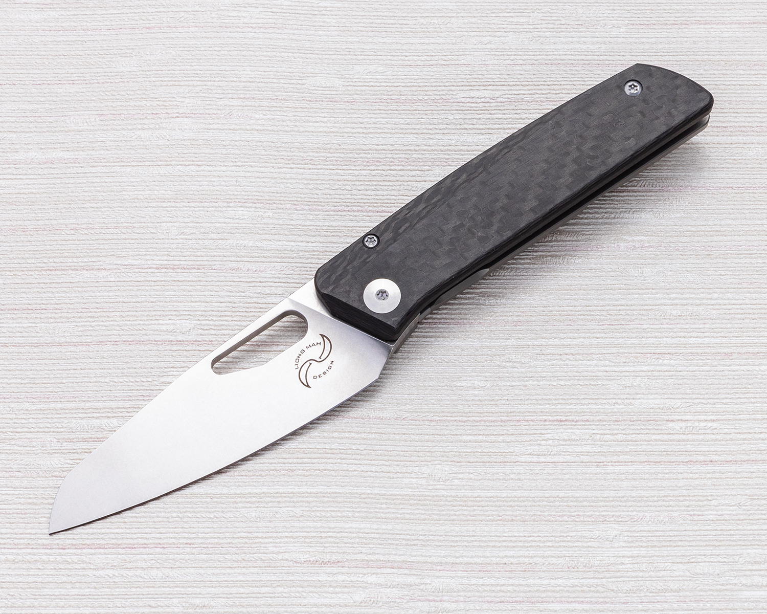 Liong Mah folding knife open on white textile background